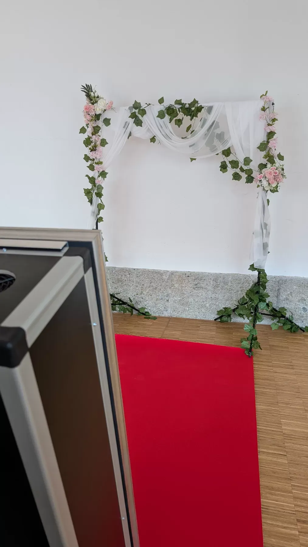 Aufgebauter Fotospiegel vor einem Blumenbogen mit rotem Teppich